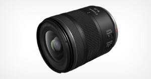 A close-up of a Canon camera lens with a sleek black design. The lens features control switches and markings for 17-28mm focal lengths. The glass element is visible, showcasing its reflective surface.