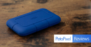 A blue LaCie rugged external hard drive lies on a wooden surface. The words "PetaPixel Reviews" are overlaid in the bottom right corner.