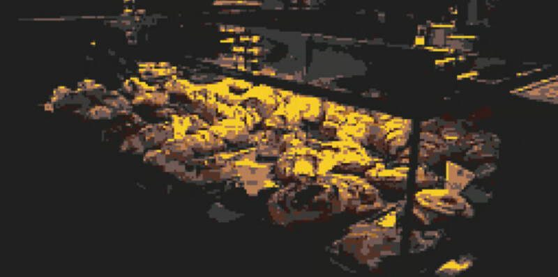 A dimly lit bakery display filled with an assortment of pastries and baked goods, including croissants and danishes, illuminated by warm, yellow light.