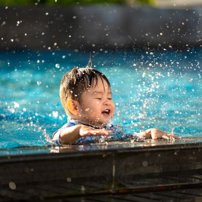 Vietnamese - Happy child playing with water splashes in the pool