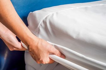 Woman is putting the bedding cover or mattress pad on the bed or putting off for cleaning process.