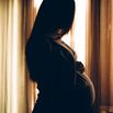 Silhouette of a pregnant woman by the window