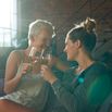 Lesbian couple sitting in sofa, toasting wine