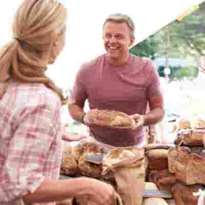 A person holding a tray of bread in a store.