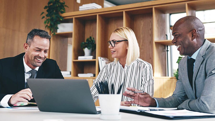 Two people sitting at a table with laptops.