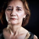 Brunette woman looking into camera against a black background.