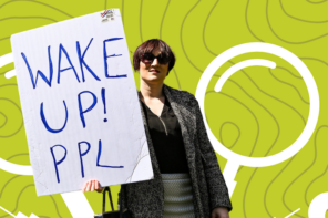 A protestor holding a sign saying "Wake Up! ppl"