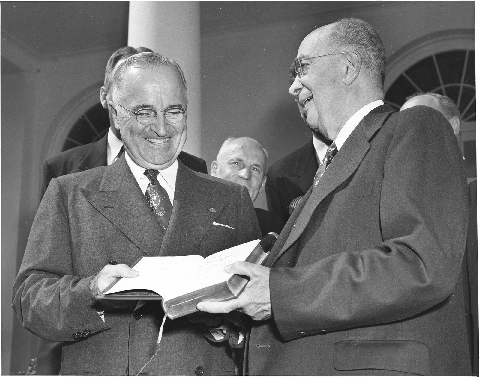 President Harry S. Truman (left) accepts a new Revised Standard Version of the Bible from Dean Emeritus of the Yale Divinity School, Dr. Luther A. Weigle (right), in a Rose Garden ceremony at the White House. Dr. Weigle gave the book on behalf of the National Council of Churches as the chairman of the American Standard Bible Committee. Fifteen years of labor by 32 Protestant scholars went into the crafting of the RSV Bible, which was written in contemporary language. Other people are unidentified.