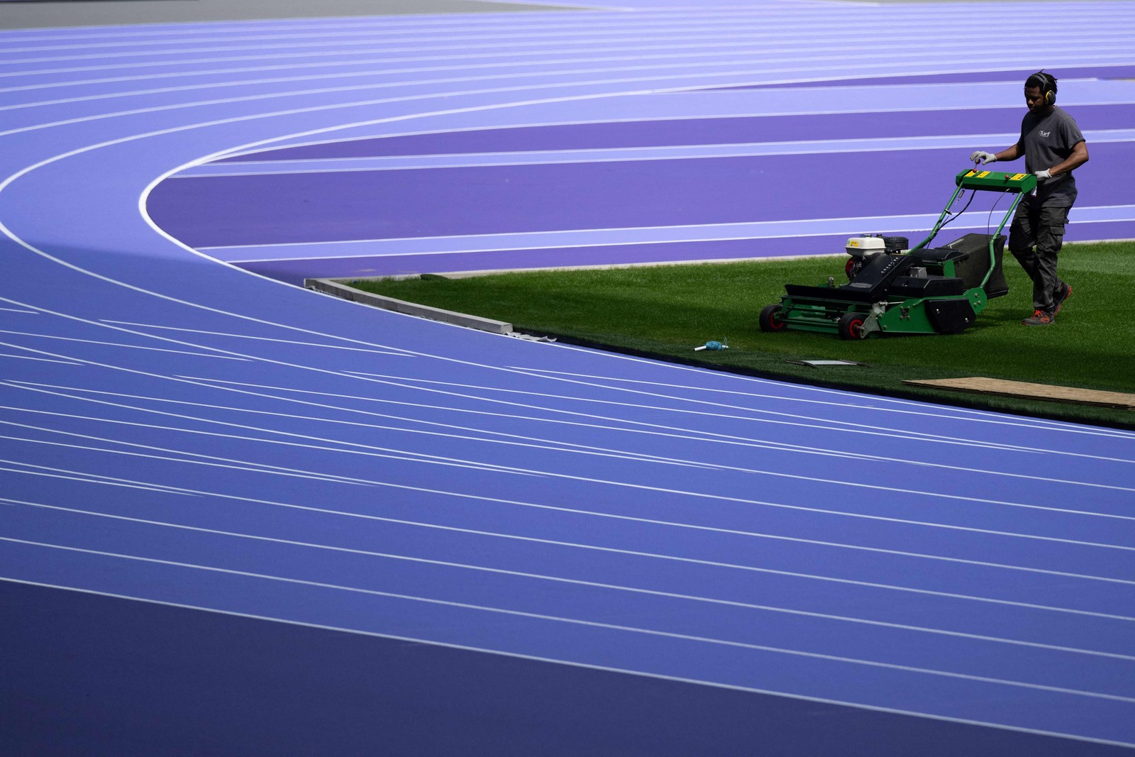 Estádios são restaurados para sediar a Olimpíadas de 2024 em Paris. Na foto, um jardineiro corta a grama do Stade de France,  em Saint-Denis — Foto: Martin BUREAU/AFP