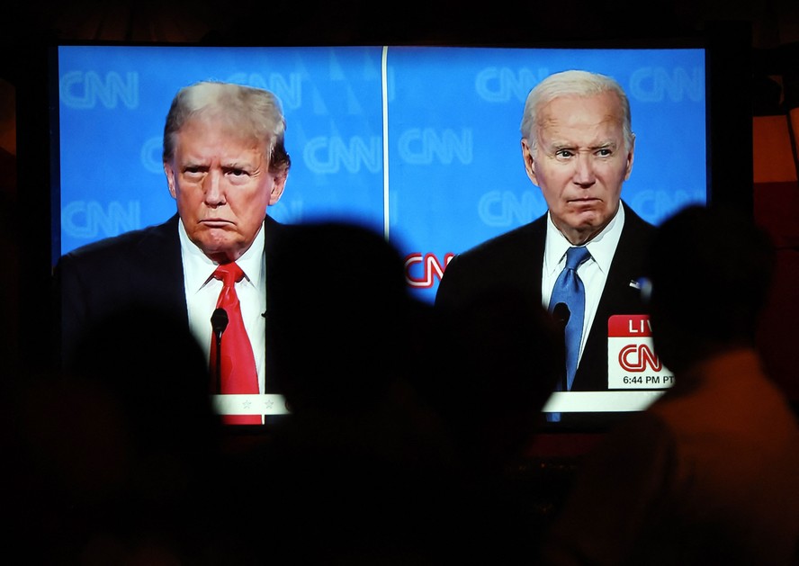 Pessoas assistem ao debate entre o ex-presidente Donald Trump (E) e o presidente dos EUA, Joe Biden