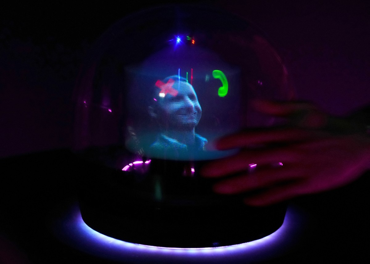 Um holograma gerado por IA chamado "Conceptt" sinalizando uma videochamada é exibido no estande da Deutsche Telekom AG durante o Mobile World Congress (MWC), o maior encontro anual da indústria de telecomunicações, em Barcelona, em 26 de fevereiro de 2024. — Foto: Pau Barrena / AFP