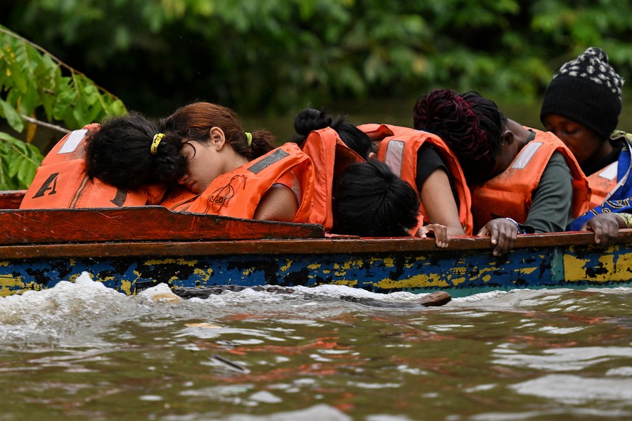 Venezuelanos dormem durante travessia de rio na selva de Darién