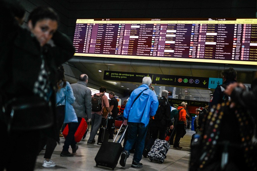 Passageiros observam painel dos voos no aeroporto de Lisboa