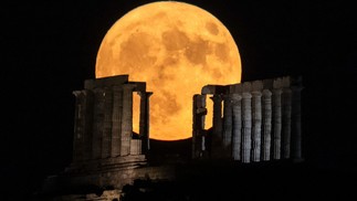 Superlua surge atrás do templo de Poseidon, no sul de Atenas — Foto: Aris MESSINIS / AFP