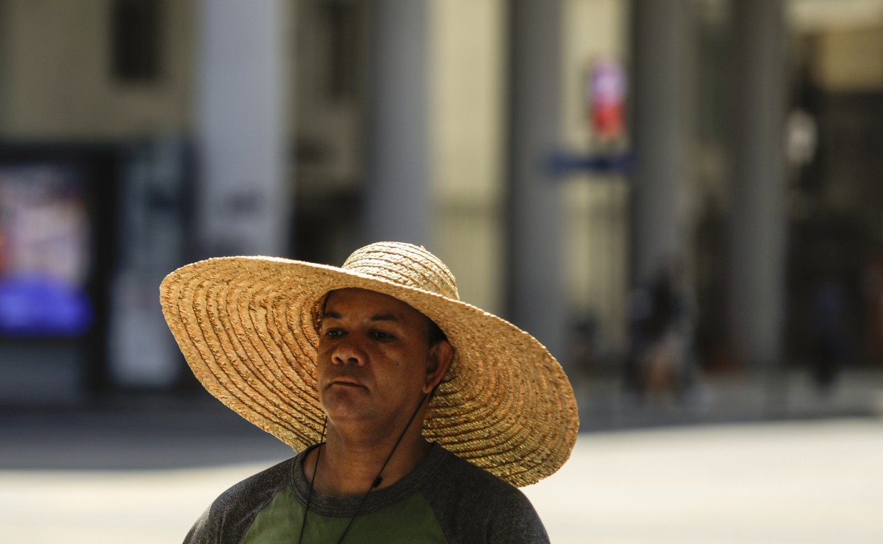 Vendedor ambulante recorre a chapéu para se proteger do sol no Centro do Rio — Foto: Gabriel de Paiva