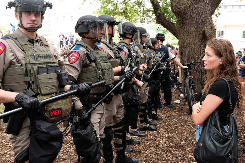 Estudante observa soldados da polícia estadual do Texas, no campus da Universidade do Texas, em Austin — Foto: SUZANNE CORDEIRO / AFP