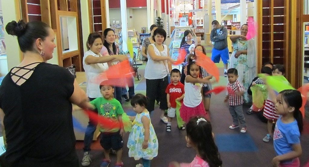 Librarian and children dancing with colorful scarves