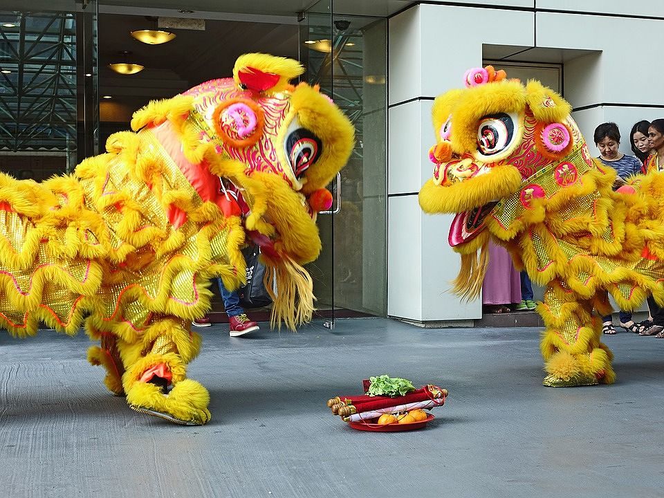 Two yellow lion dance performers outdoors.