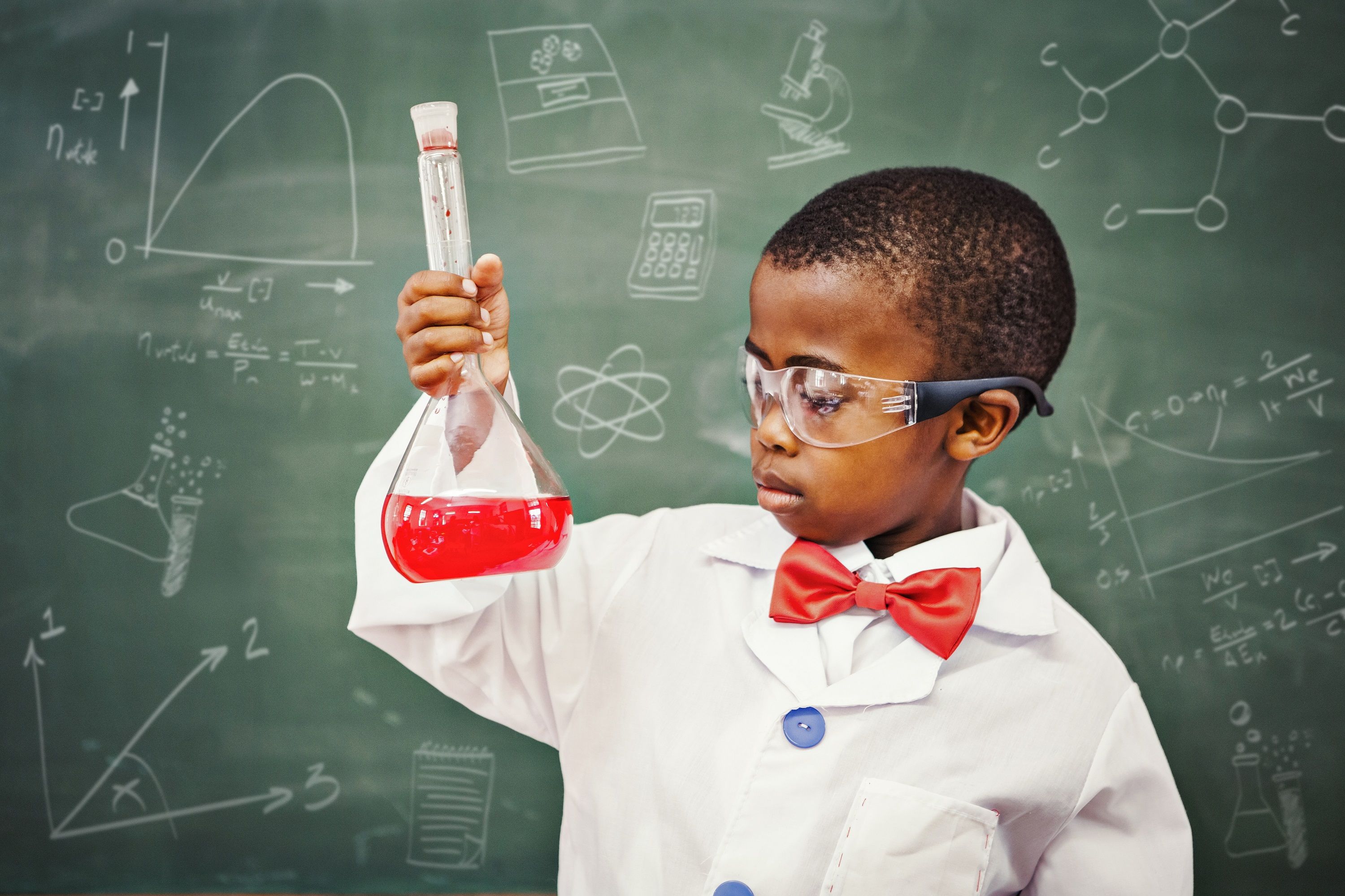 stock photo of a young boy in a lab coat with a flask