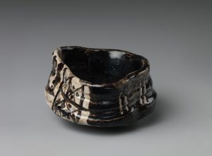 Clog-shaped tea bowl with plum-blossom motifs and geometric patterns, early 17th century, stoneware with iron-black glaze, Mino ware, black Oribe type, H. 7.6 cm; W. 14.3 cm; diam. of foot 5.7 cm (Metropolitan Museum of Art) 