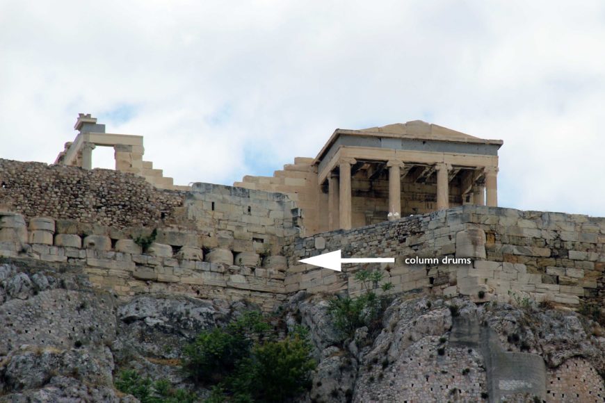 Remains of materials from the temples destroyed during the Persian sack of the Acropolis, such as column-drums (here) and a triglyph-metope frieze, were incorporated into the Acropolis North Wall.