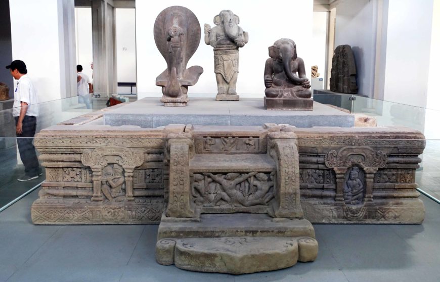 Altar-pedestal with god Skanda and two Ganesha sculptures (right to left), 7th-8th century, Mỹ Sơn E1, Vietnam, sandstone, H. 65 cm; W. 271 cm, D. 333 cm (Đà Nẵng Museum of Cham Sculpture; photo: Daderot, CC0 1.0)