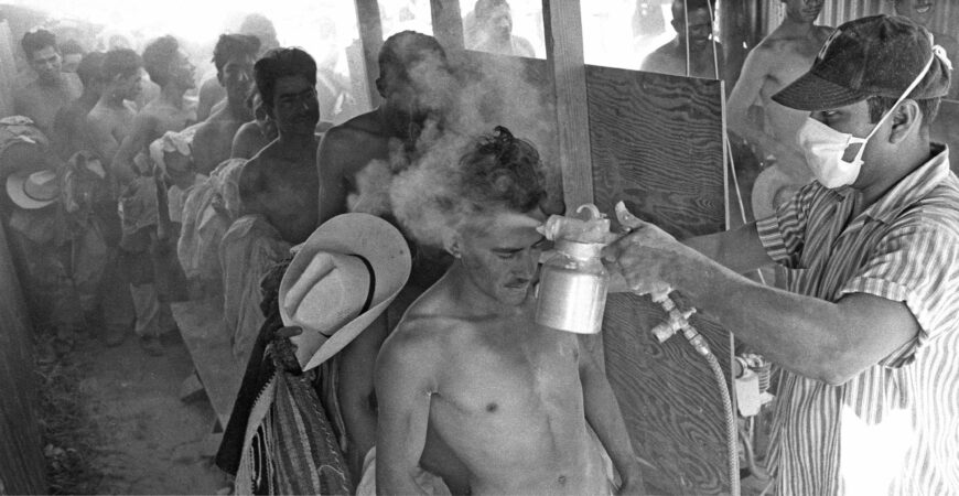 Leonard Nadel, A masked worker fumigates a bracero with DDT at the Hidalgo Processing Center, Texas, while others wait in line, 1956, gelatin silver print (National Museum of American History, Archives Center, Washington, D.C.)