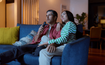 Couple  sitting on the couch watching television.