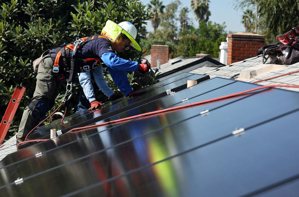 A worker installs solar panels on a home's roof.