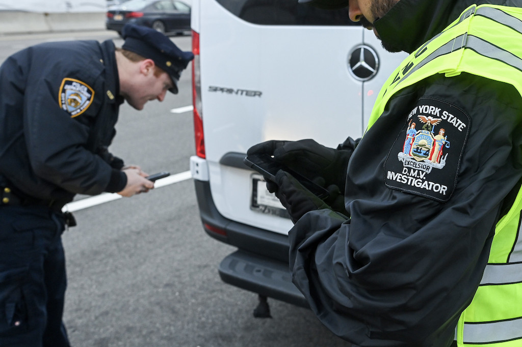 Law enforcement personnel in New York examine a license plate.