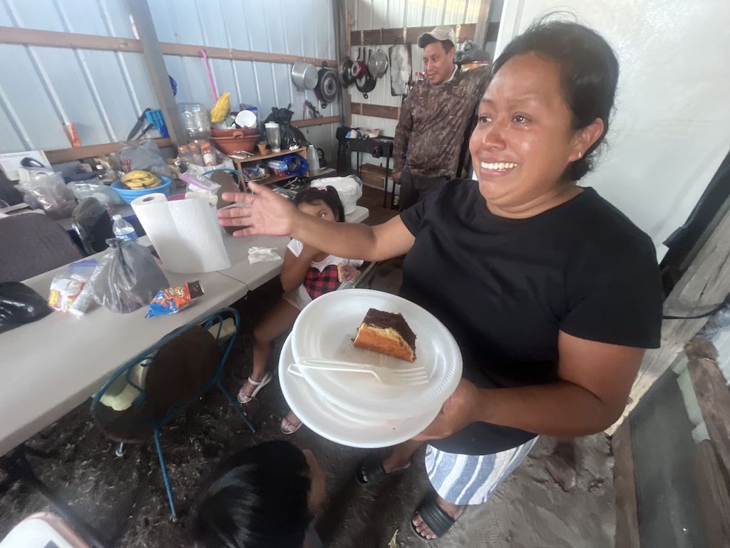 A woman holds a plate of flan.