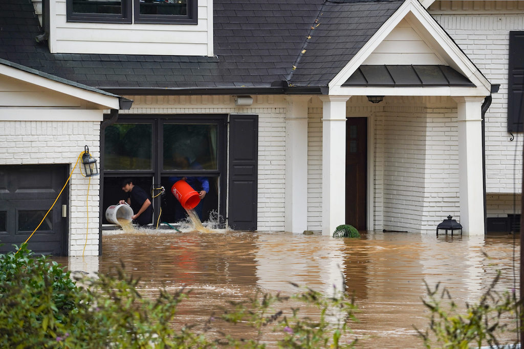 People dump water out of a flooded house.