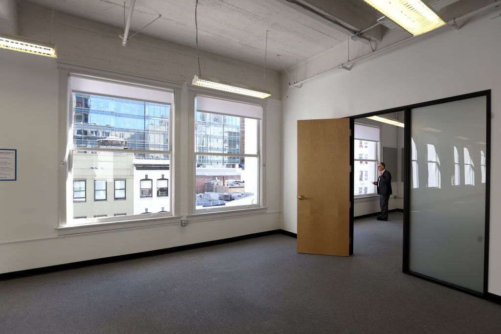 A man looks out the window of a vacant office building.