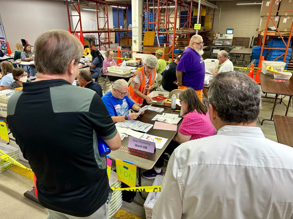 People observe poll workers.