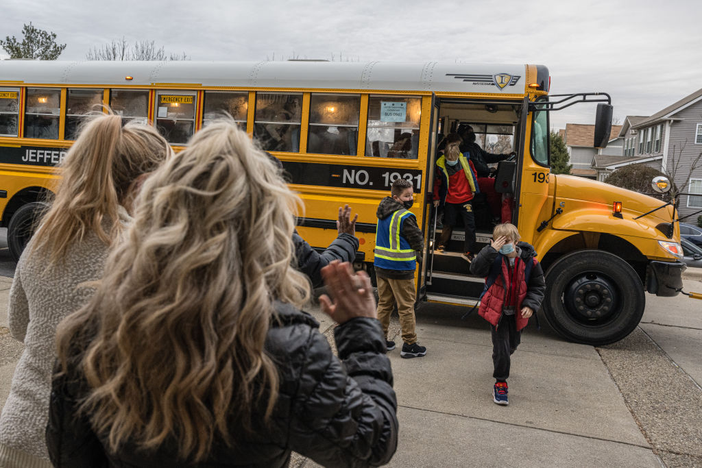 Teachers greet students getting off a school bus in Louisville, Ky.