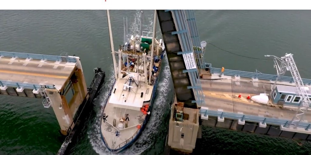 A boat passes through a raised bridge.