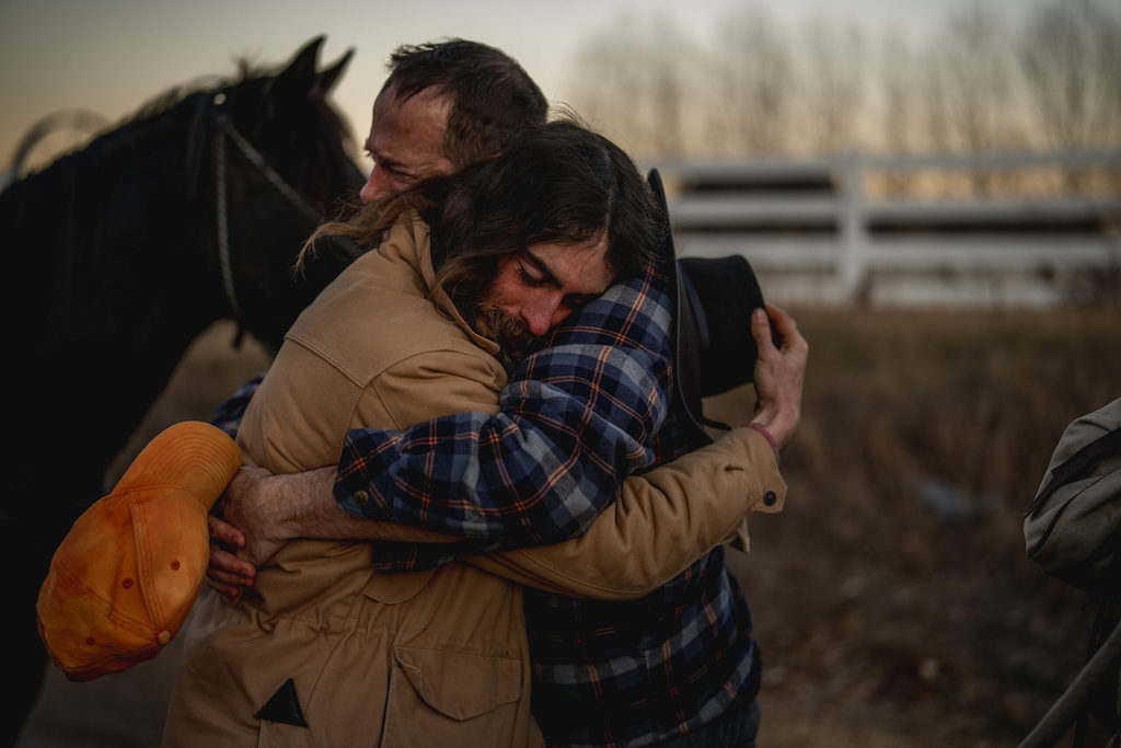 Two men hug.