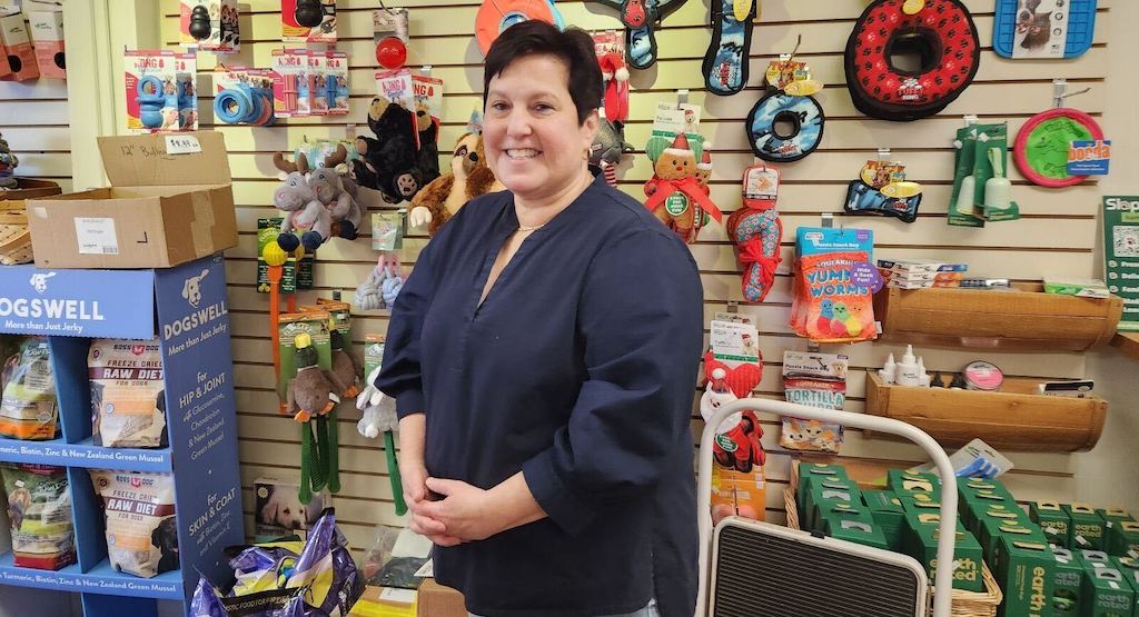 A woman stands in her pet store.