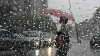 Un pedone con l'ombrello attraversa la strada durante un temporale a Buenos Aires, in Argentina, il 20 marzo 2024.