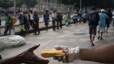 Personas sin hogar se reúnen para tomar café y comer pan en Río de Janeiro, Brasil, en marzo de 2020.