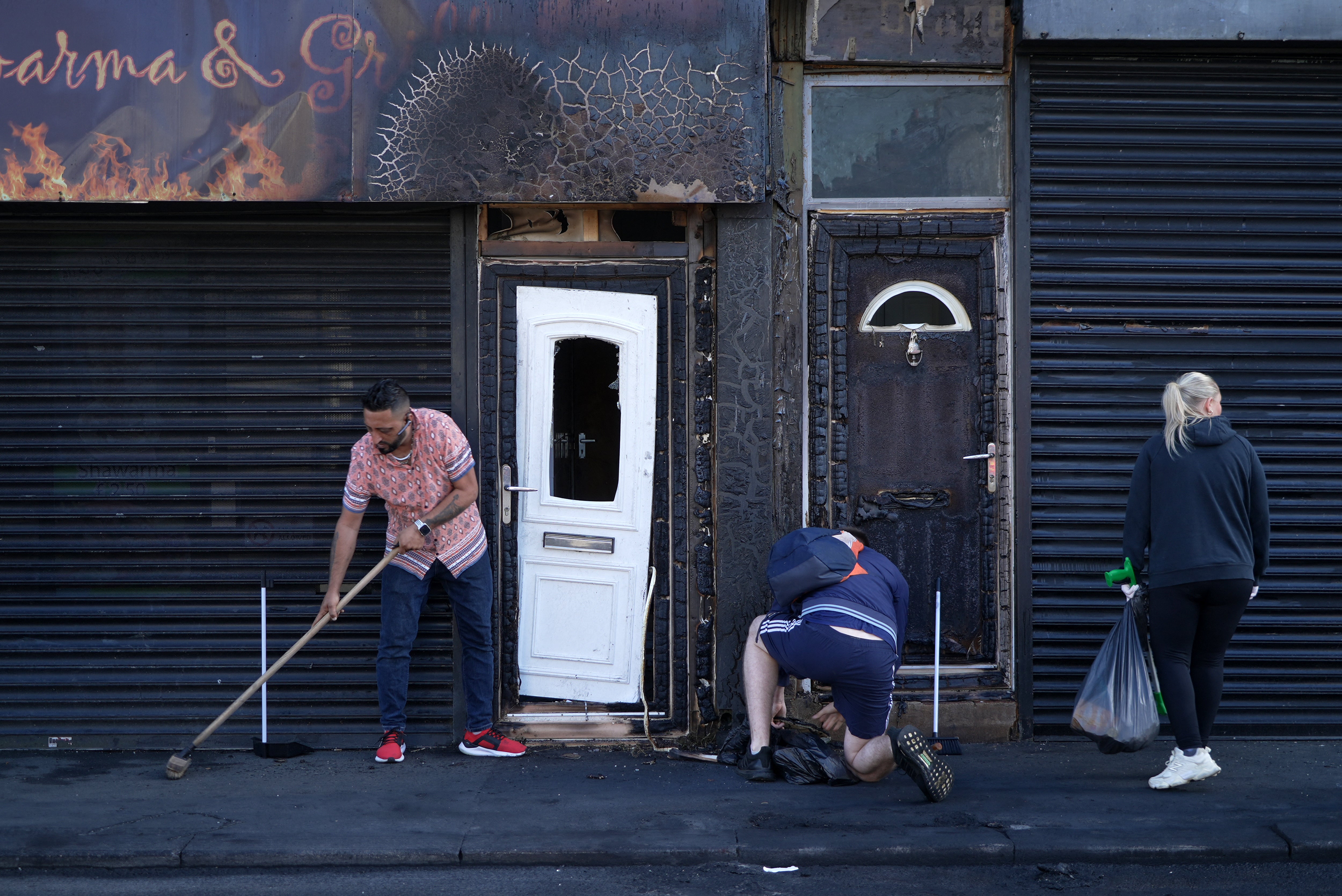 A restaurant owner clears debris from the street in front of his restaurant in Middlesbrough, following rioting and looting