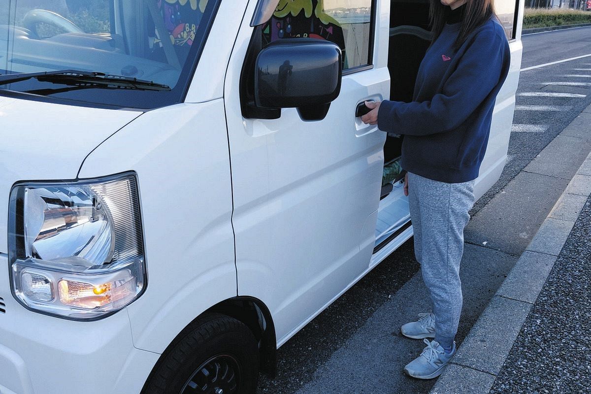 配達に使う軽貨物車の前に立つ女性