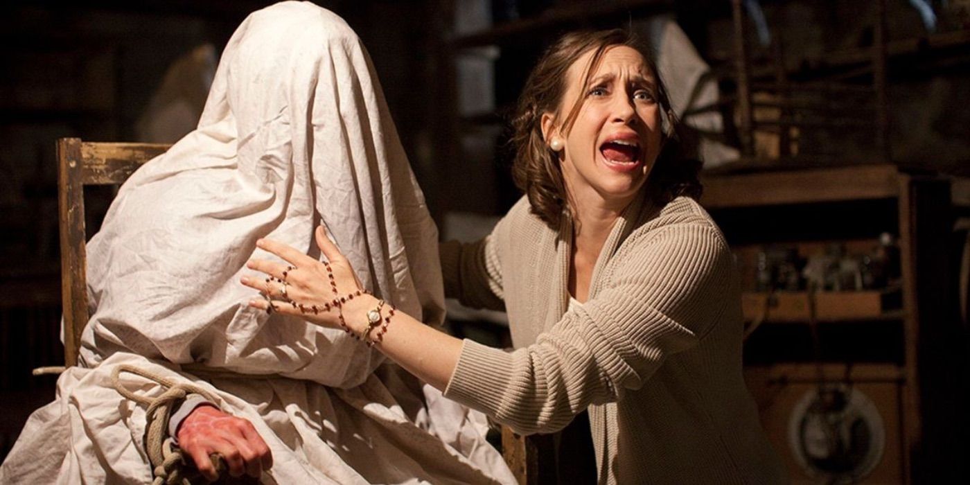 Lorraine Warren, played by Vera Farmiga, screams while standing next to a possessed person covered by a sheet in 'The Conjuring'.