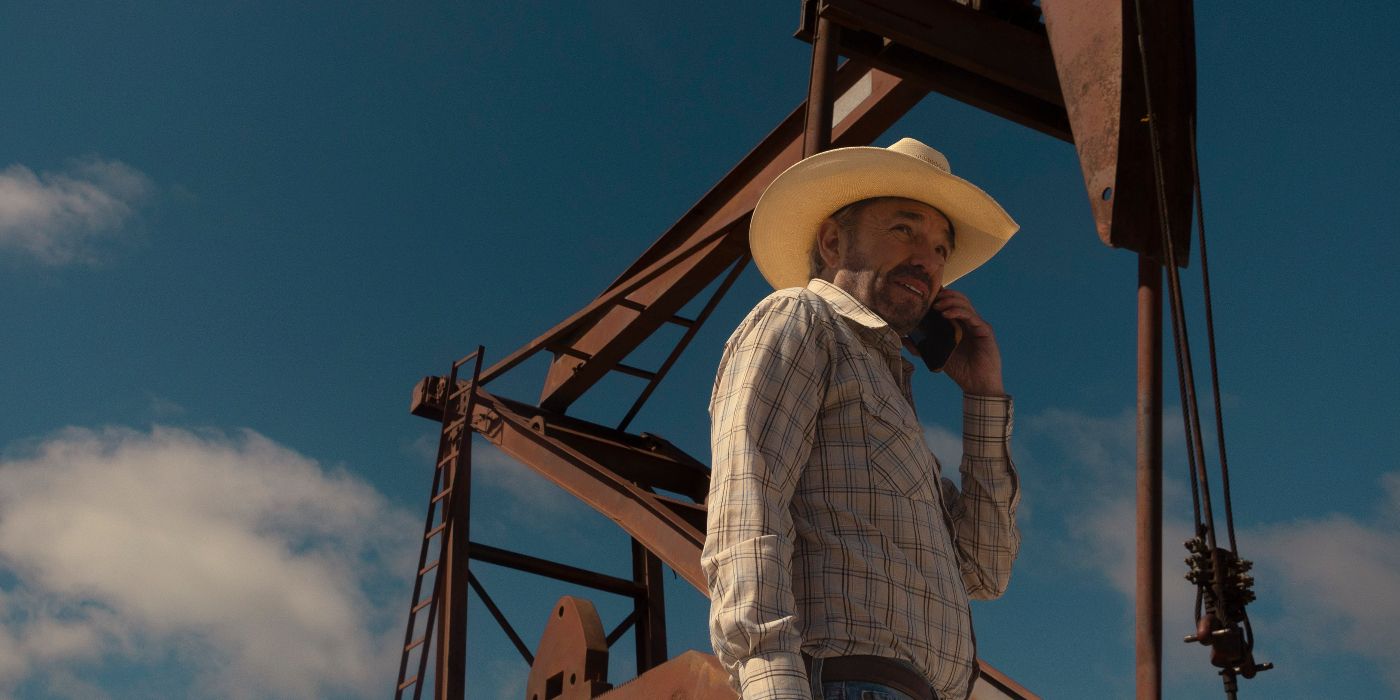 Tommy Norris (Billy Bob Thornton) talking on his phone while standing outside in front of oil rig equipment in Landman