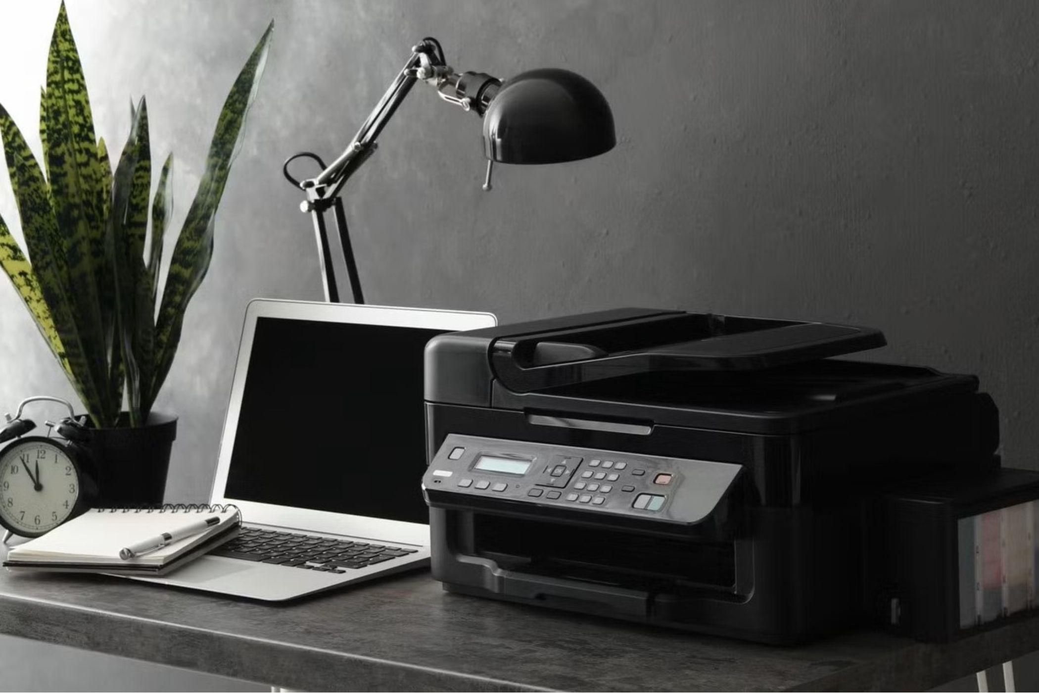 A work desk with a laptop and a printer