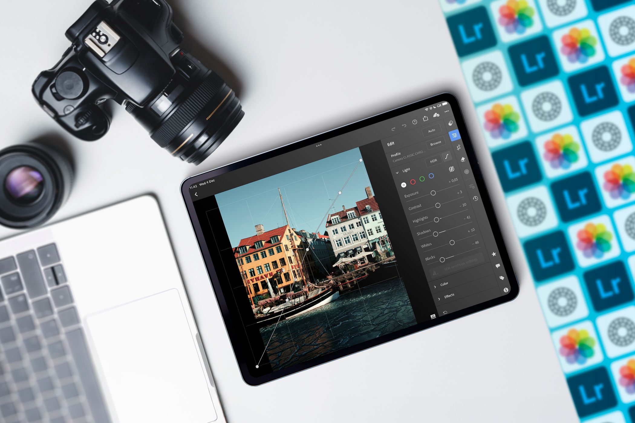 An iPad with a photo editor open, a camera, and a MacBook next to it.