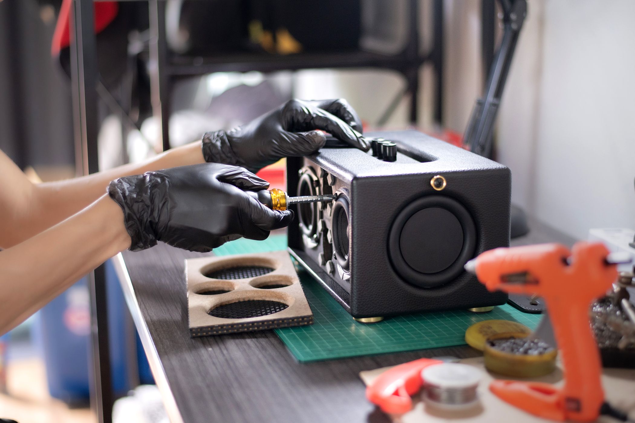 person using screwdriver to open speaker on workbench