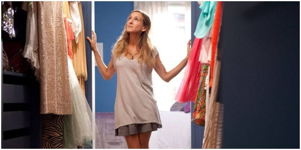 SATC's Carrie Bradshaw standing in her walk in closet looking at clothes