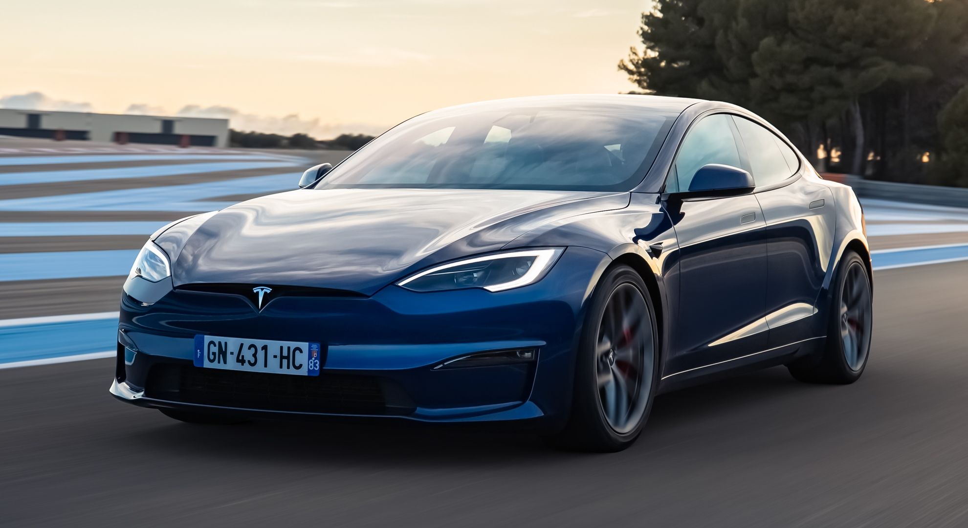 A front-quarter tracking shot of a blue Tesla Model S Plaid driving on track.