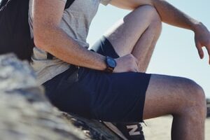 smiling man sitting on gray rock at daytime